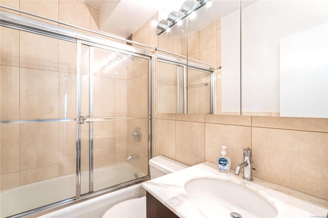 full bathroom featuring vanity, shower / bath combination with glass door, decorative backsplash, toilet, and tile walls