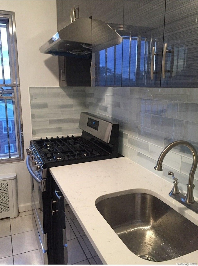 kitchen with exhaust hood, sink, stainless steel gas stove, decorative backsplash, and light tile patterned flooring