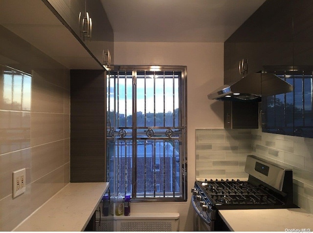 kitchen with decorative backsplash, stainless steel gas stove, and exhaust hood