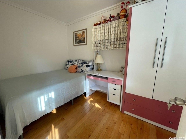 bedroom with light hardwood / wood-style floors and crown molding