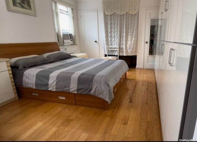 bedroom with cooling unit and light hardwood / wood-style flooring