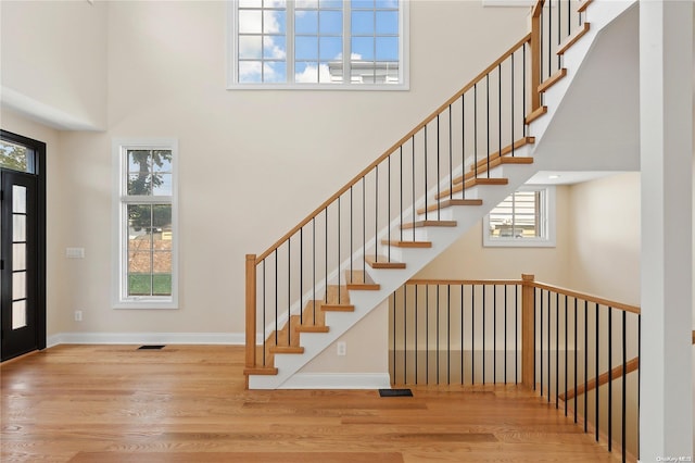 entryway with a high ceiling, light wood-type flooring, and plenty of natural light