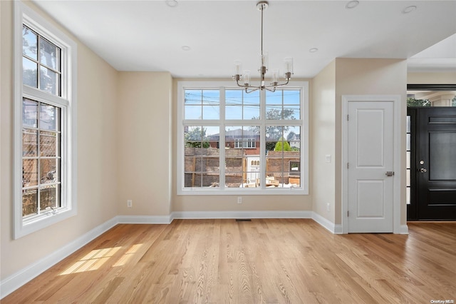 unfurnished dining area with a chandelier and light hardwood / wood-style flooring