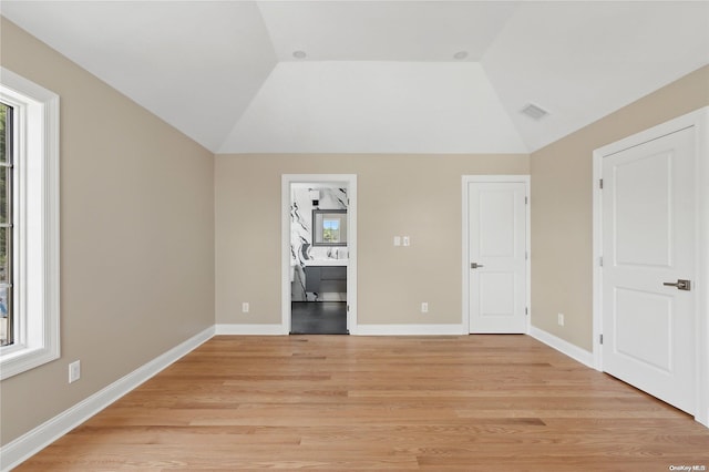 unfurnished bedroom featuring light hardwood / wood-style floors and lofted ceiling