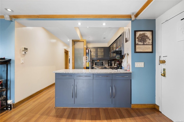 kitchen with kitchen peninsula, light stone counters, stainless steel appliances, and light wood-type flooring