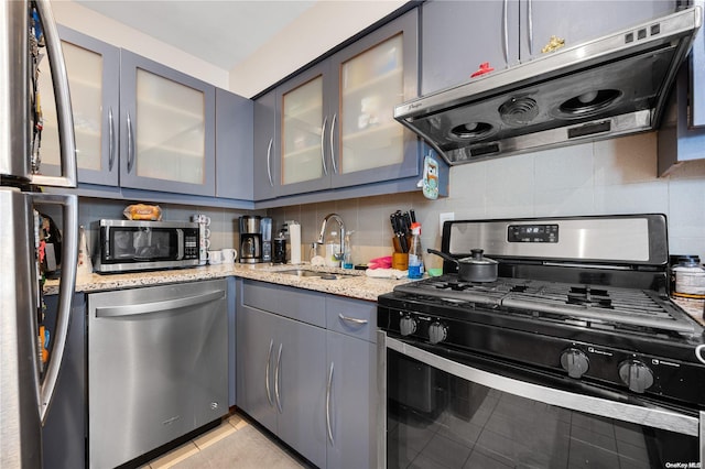 kitchen featuring light stone countertops, appliances with stainless steel finishes, extractor fan, and sink