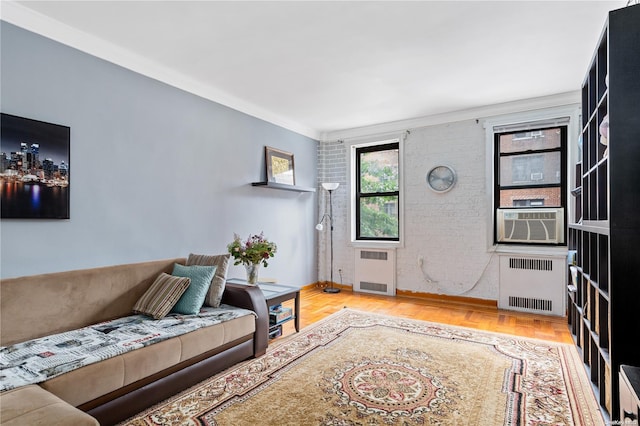 living room featuring radiator heating unit, cooling unit, ornamental molding, and light hardwood / wood-style flooring