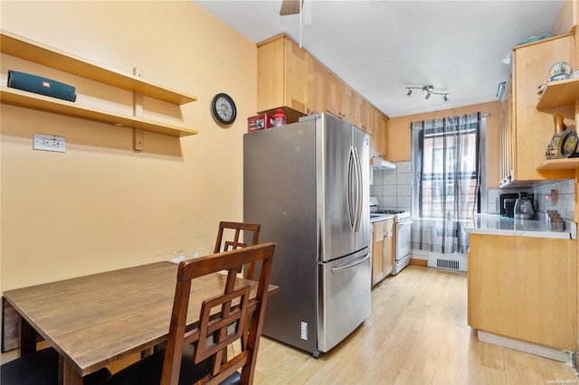 kitchen with light brown cabinets, backsplash, gas range gas stove, light hardwood / wood-style floors, and stainless steel refrigerator