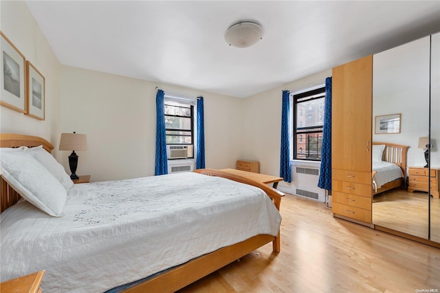 bedroom with cooling unit, radiator, and light hardwood / wood-style flooring