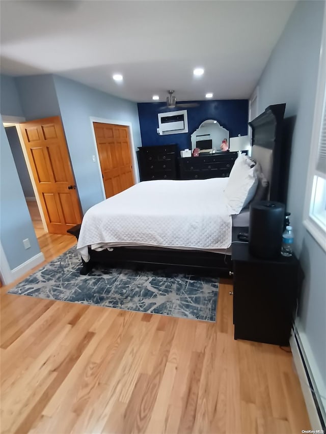 bedroom with hardwood / wood-style flooring and a baseboard heating unit