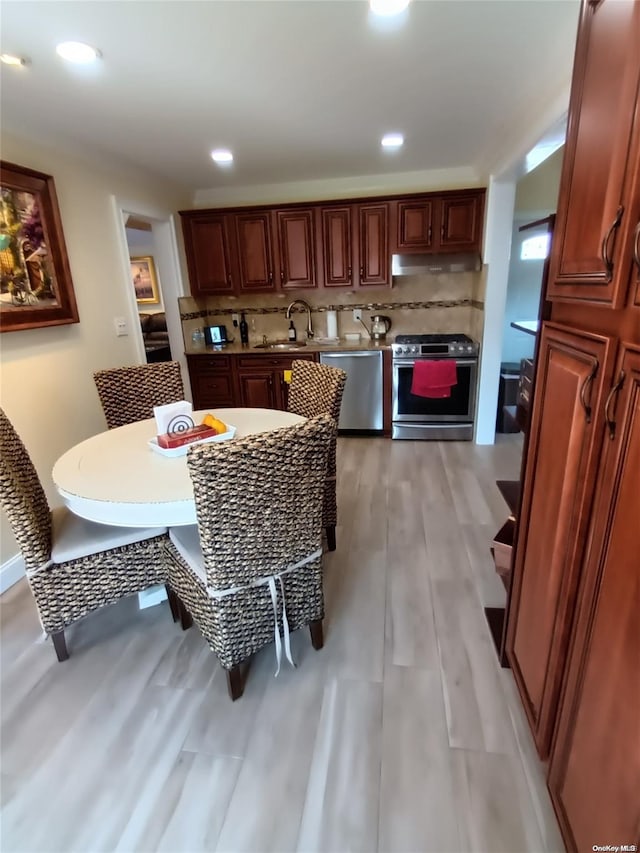 kitchen featuring appliances with stainless steel finishes, tasteful backsplash, light hardwood / wood-style flooring, and sink