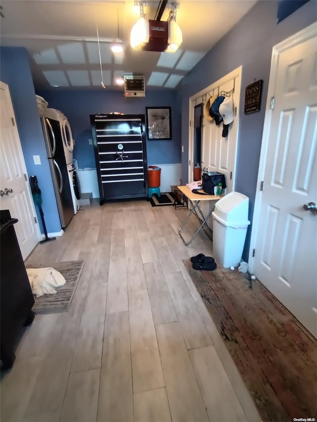 garage featuring stainless steel fridge, stacked washing maching and dryer, and a garage door opener