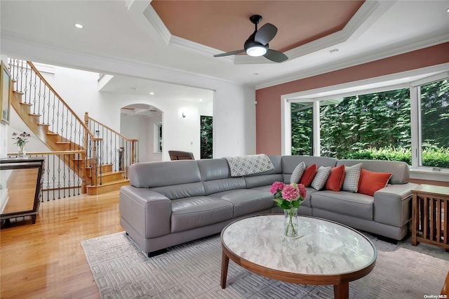 living room with a tray ceiling, crown molding, ceiling fan, and light hardwood / wood-style floors