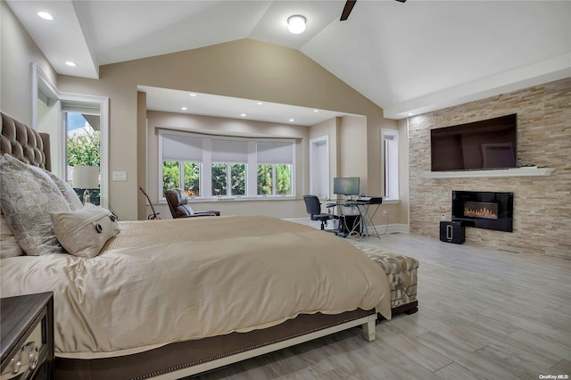 bedroom with a fireplace, light wood-type flooring, ceiling fan, and lofted ceiling