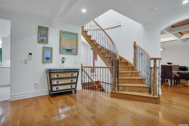 staircase featuring beam ceiling, hardwood / wood-style floors, coffered ceiling, and ornamental molding