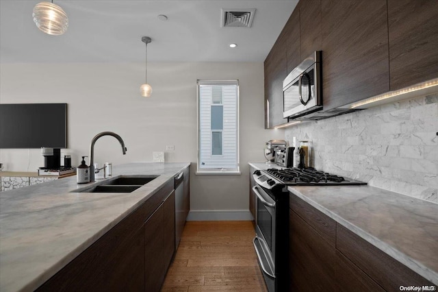 kitchen featuring pendant lighting, sink, light wood-type flooring, and stainless steel appliances