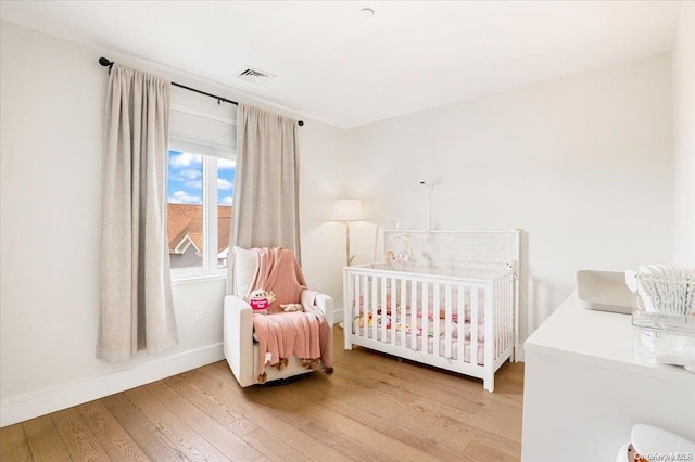 bedroom with hardwood / wood-style floors and a nursery area