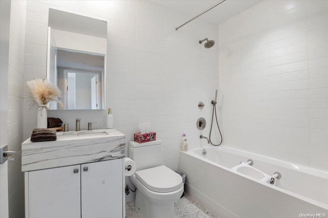 full bathroom with tile patterned floors, vanity, tiled shower / bath combo, tile walls, and toilet