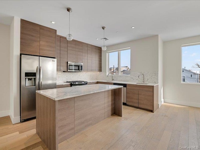 kitchen with decorative light fixtures, light hardwood / wood-style flooring, appliances with stainless steel finishes, a healthy amount of sunlight, and decorative backsplash