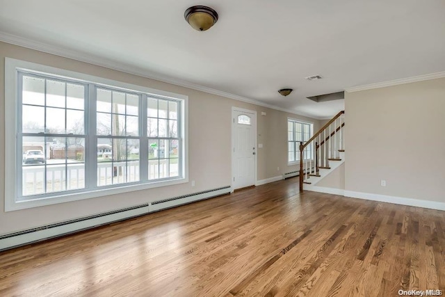 foyer featuring hardwood / wood-style floors, crown molding, a wealth of natural light, and a baseboard heating unit