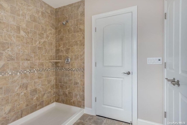 bathroom with a tile shower and tile patterned flooring