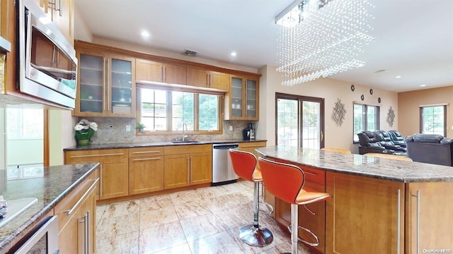 kitchen featuring appliances with stainless steel finishes, tasteful backsplash, sink, an inviting chandelier, and a kitchen island