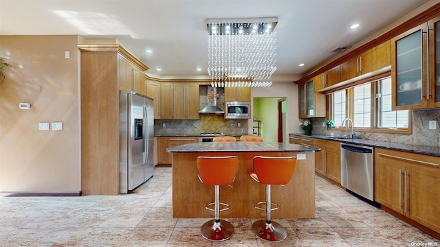 kitchen featuring a center island, wall chimney range hood, sink, a kitchen bar, and stainless steel appliances