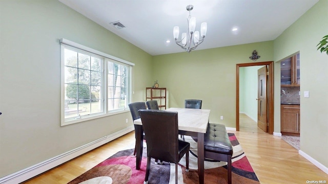 dining space featuring light hardwood / wood-style floors, an inviting chandelier, and baseboard heating