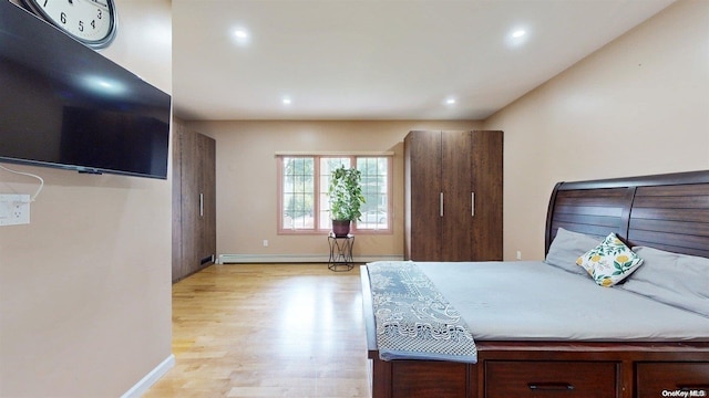 bedroom with baseboard heating and light hardwood / wood-style flooring