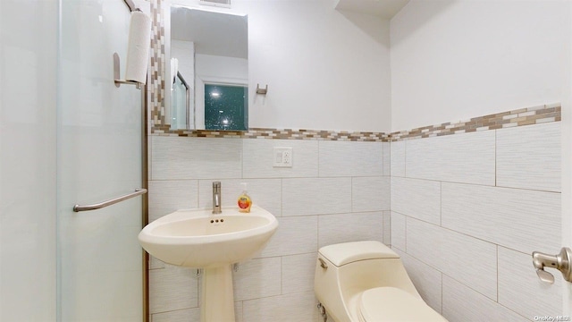 bathroom with toilet and tile walls