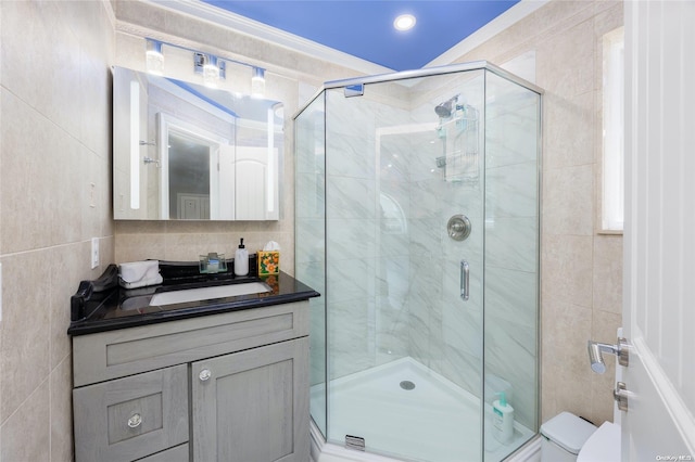 bathroom with vanity, crown molding, toilet, tile walls, and walk in shower