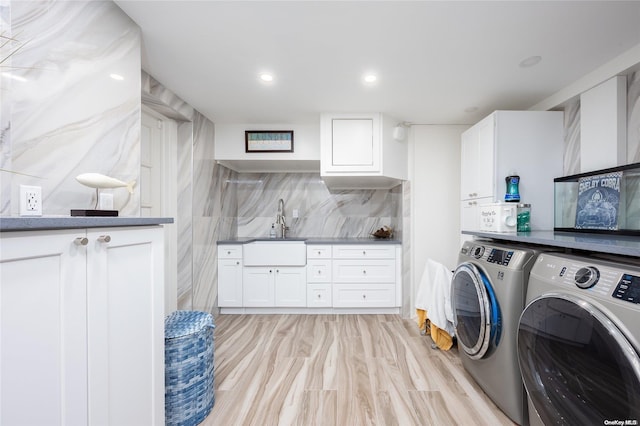 clothes washing area featuring separate washer and dryer, sink, cabinets, and light wood-type flooring