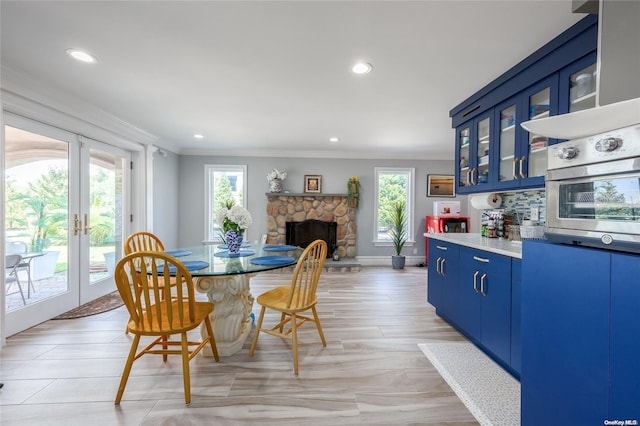 dining area featuring a stone fireplace, french doors, and ornamental molding