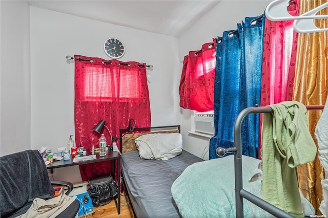 bedroom featuring hardwood / wood-style floors, vaulted ceiling, and cooling unit