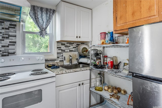 kitchen featuring white cabinets, electric range, stainless steel refrigerator, and backsplash