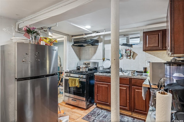 kitchen with light stone countertops, light hardwood / wood-style flooring, ventilation hood, decorative backsplash, and appliances with stainless steel finishes