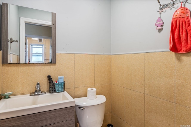 bathroom featuring vanity, toilet, and tile walls