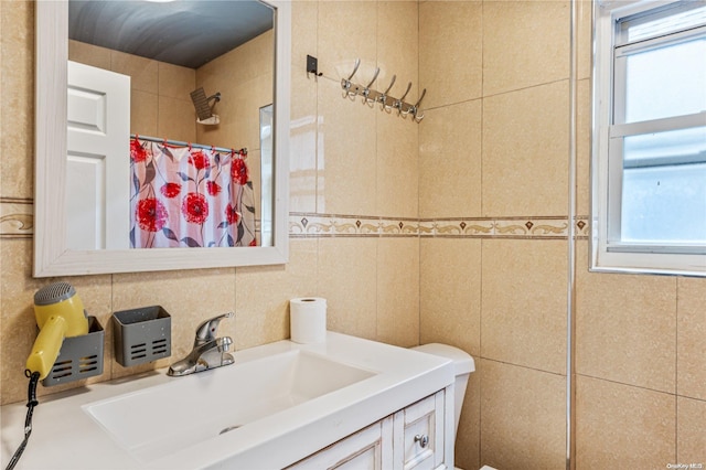 bathroom with a wealth of natural light, vanity, and tile walls