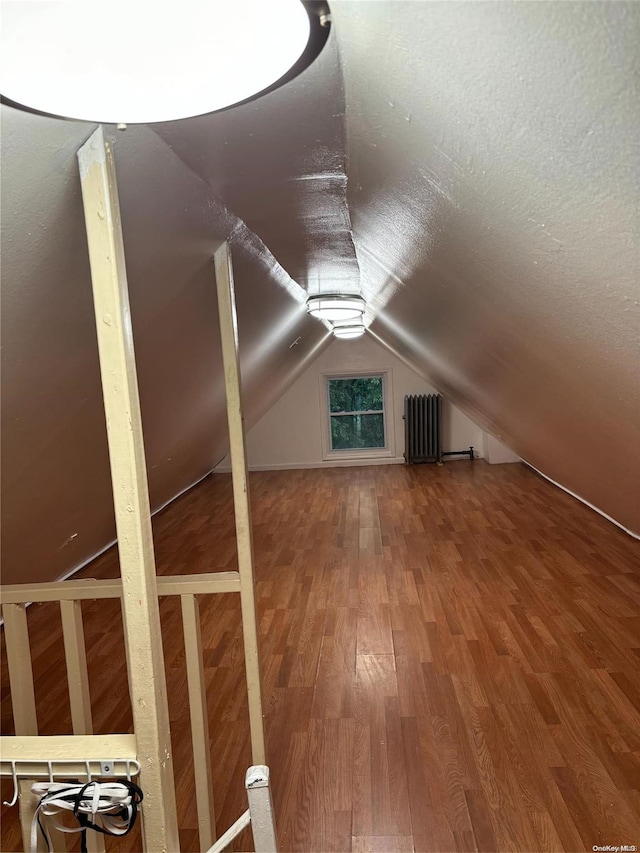 additional living space featuring radiator heating unit, hardwood / wood-style flooring, and vaulted ceiling