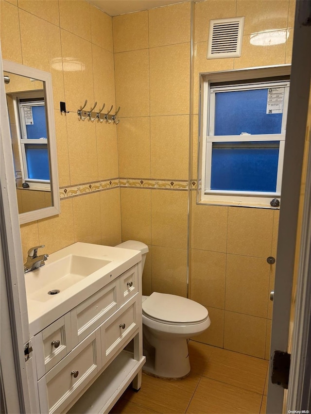 bathroom featuring vanity, toilet, and tile walls