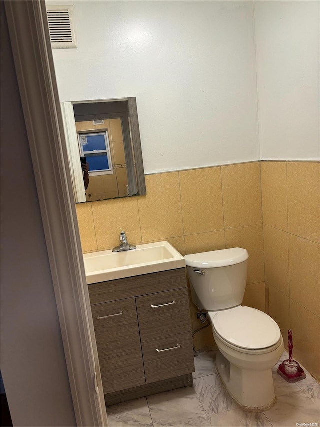 bathroom featuring vanity, toilet, and tile walls