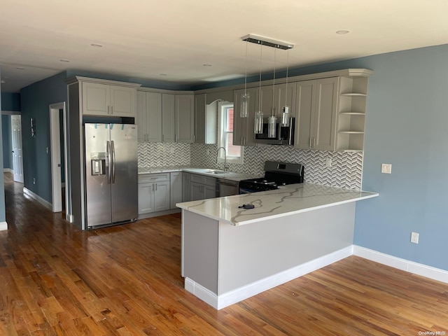 kitchen featuring kitchen peninsula, dark hardwood / wood-style flooring, stainless steel appliances, sink, and hanging light fixtures