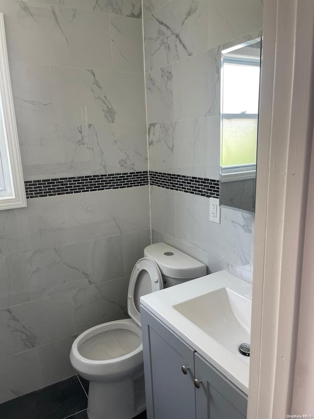 bathroom with vanity, toilet, and tile walls