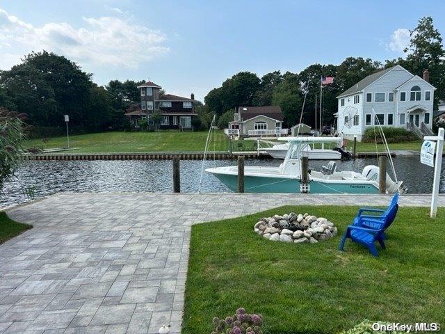 view of home's community featuring a water view, a dock, and a lawn