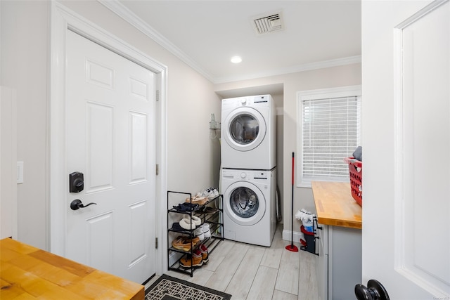 clothes washing area with ornamental molding and stacked washer and clothes dryer