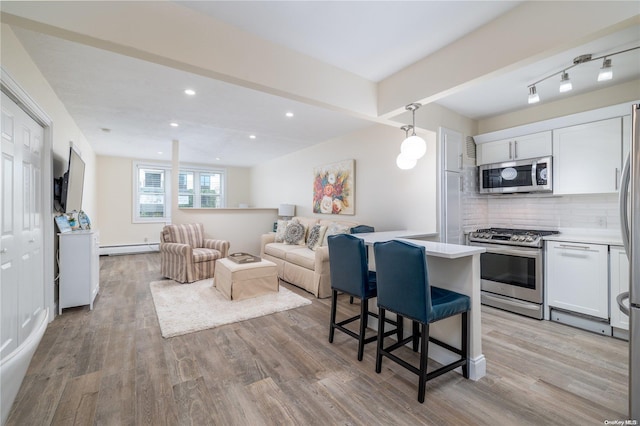 kitchen with white cabinetry, light hardwood / wood-style floors, a baseboard radiator, and appliances with stainless steel finishes