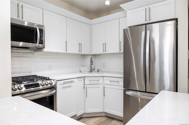 kitchen featuring backsplash, white cabinetry, light hardwood / wood-style flooring, and appliances with stainless steel finishes