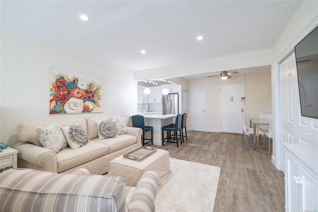 living room with light hardwood / wood-style flooring and ceiling fan