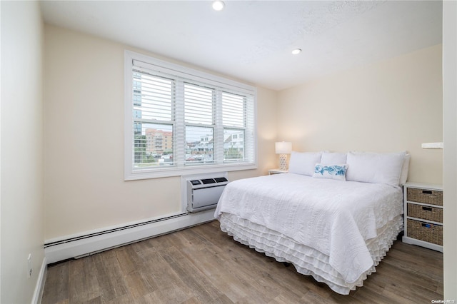 bedroom featuring wood-type flooring, baseboard heating, and a wall unit AC