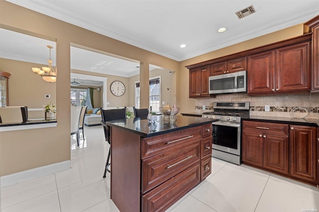 kitchen with decorative backsplash, light tile patterned floors, stainless steel appliances, and a kitchen island